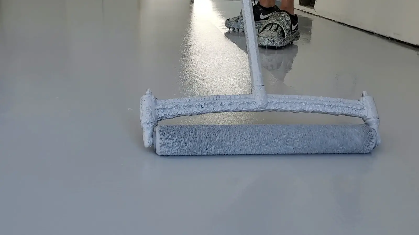 Roller applying a gray epoxy basecoat